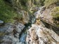 Hikers wearing helmets climbing through a watery gorge.